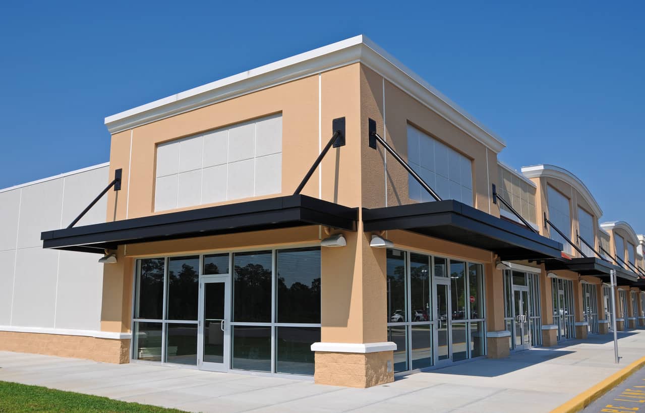 Commercial Building Exterior Painting Peach-colored commercial building exterior with white trim, black awning, and large storefront windows in Saint Charles, IL
