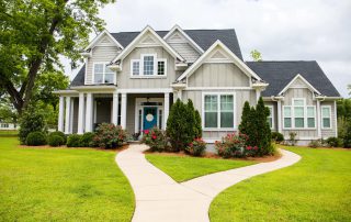 Cream-painted two-story residential home with white trim, dark gray roof, and white columns on Saint Charles property