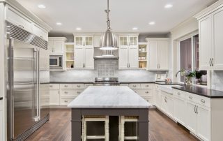 Cream-painted kitchen cabinetry with white countertop, gray island, stainless steel appliances, and pendant lighting