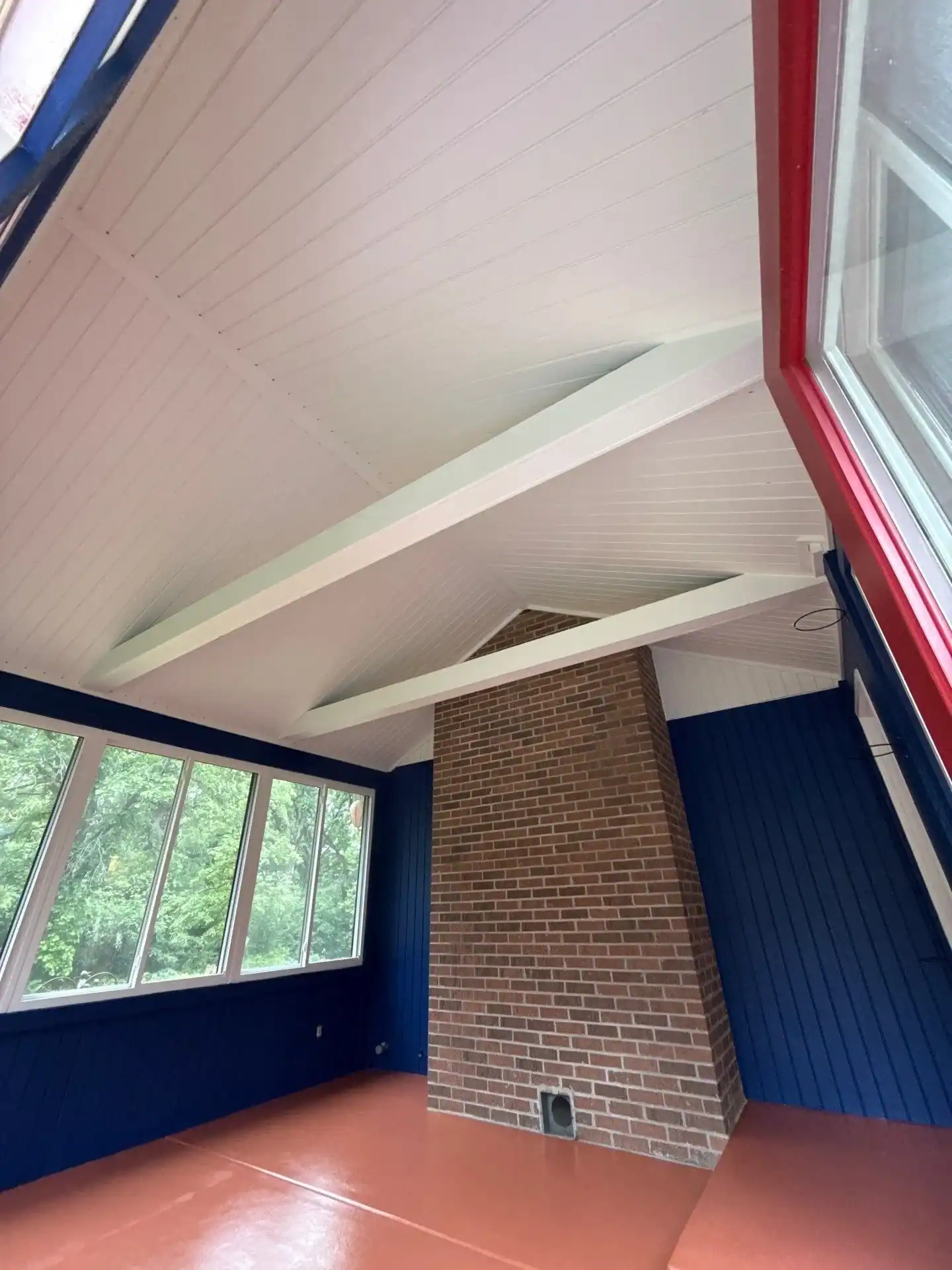 Navy Blue Commercial Interior Painting Navy blue painted interior commercial space with white coffered ceiling, brick chimney, and red-orange concrete floor.
