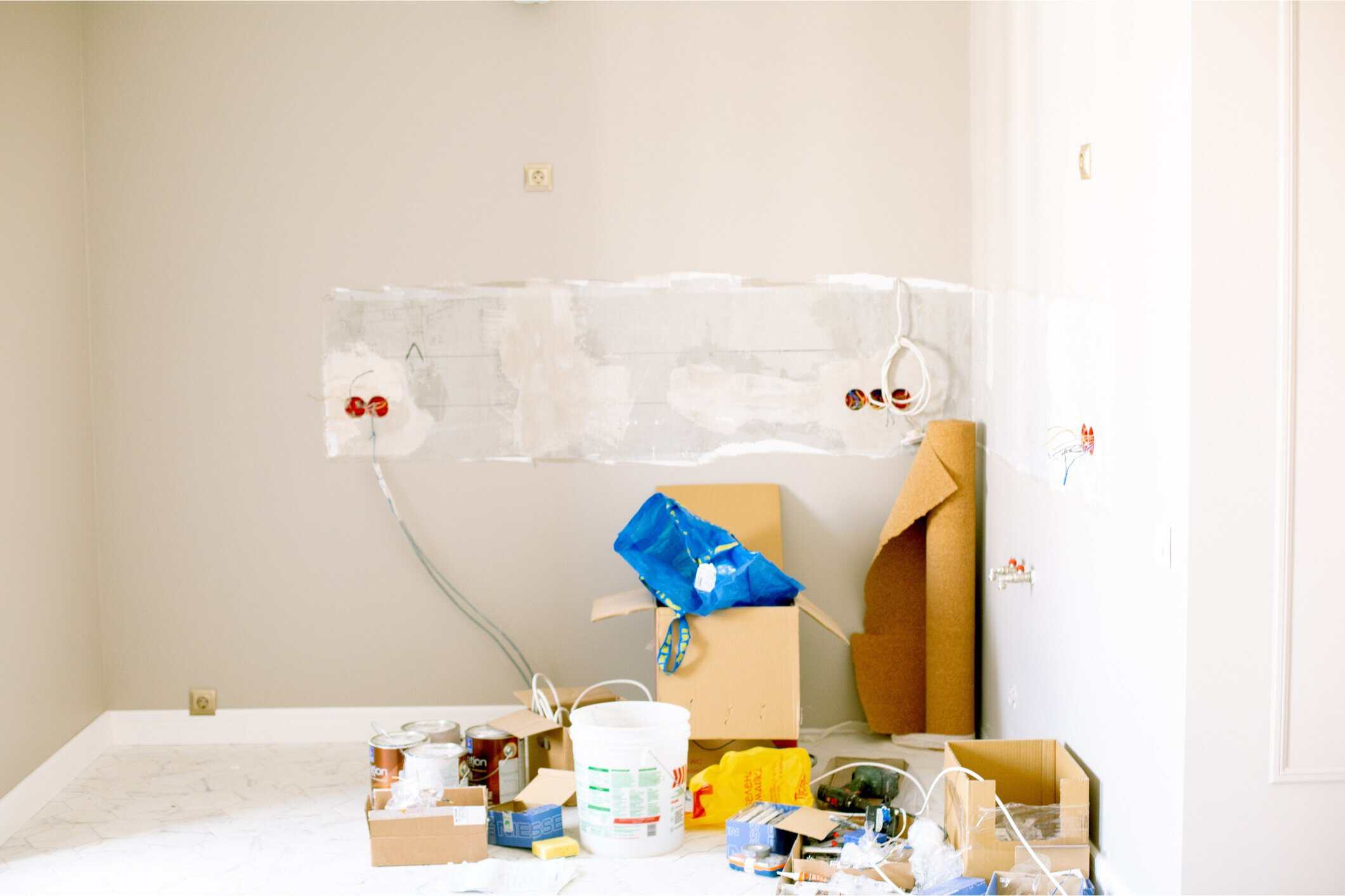 Cream Interior Wall Painting Preparation Cream-colored interior wall with protective plastic sheeting, painter's supplies, and cardboard boxes during residential