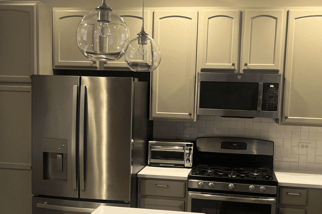 Cream-painted kitchen cabinets with stainless steel appliances, white subway tile backsplash, and pendant lighting.