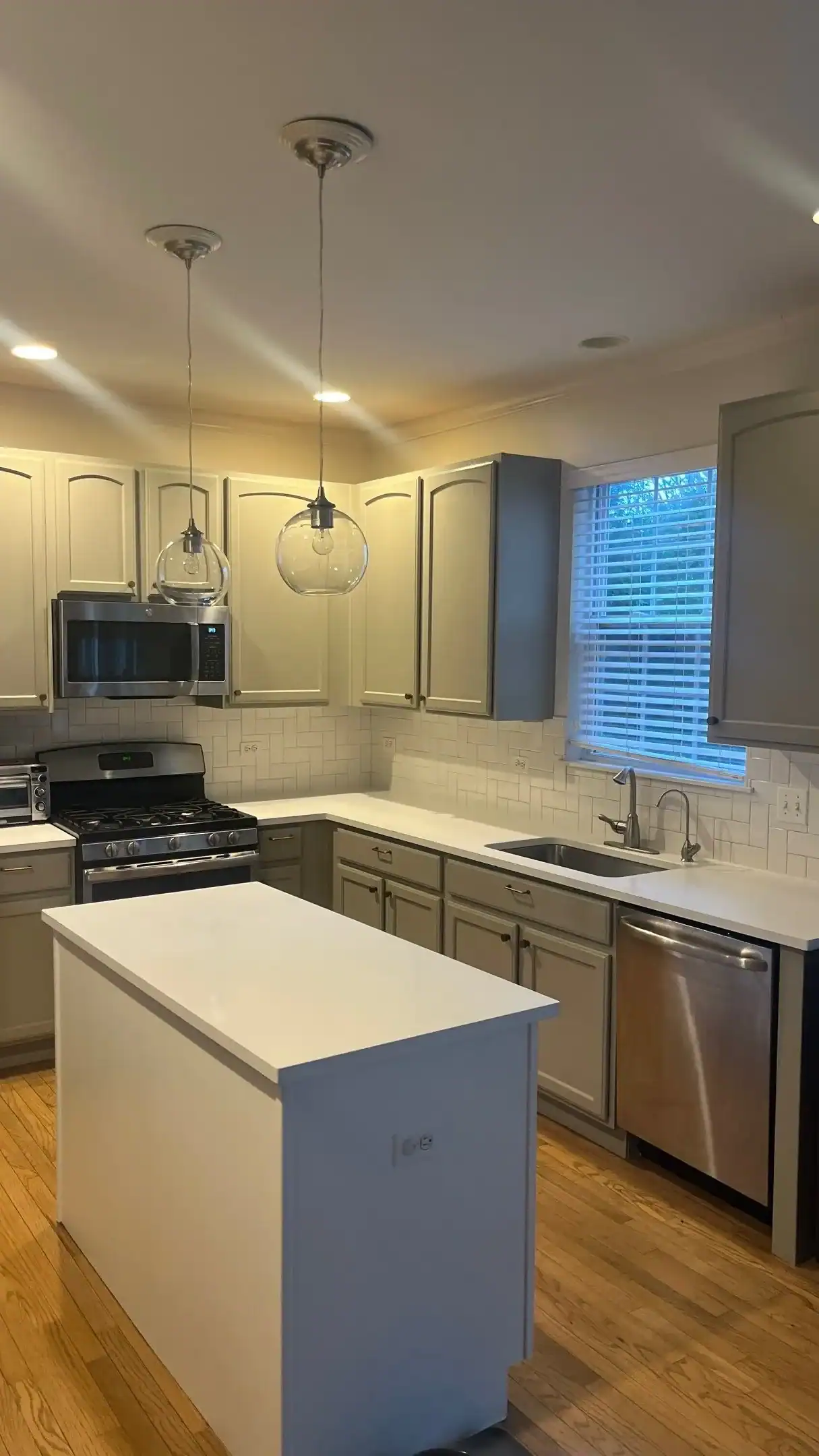 Cream And Blue Painted Kitchen Interior Cream-painted kitchen cabinets with blue island, white quartz countertops, white subway tile backsplash, and stainless steel