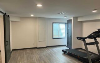 Cream-painted commercial interior with light wood-look flooring, recessed ceiling lights, and black treadmill equipment