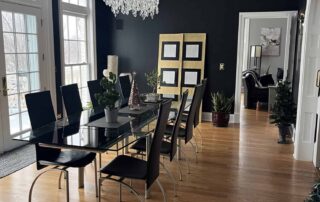 Navy-painted dining room with white ceiling molding, crystal chandelier, black dining table, and wood flooring in Saint