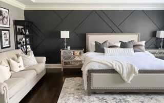 Charcoal gray bedroom accent wall with geometric diamond pattern, cream ceiling, upholstered bed frame, and cream seating