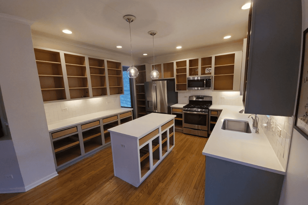 White Kitchen Cabinetry Commercial Interior White-painted commercial kitchen interior with natural wood shelving, white quartz countertops, stainless steel appliances