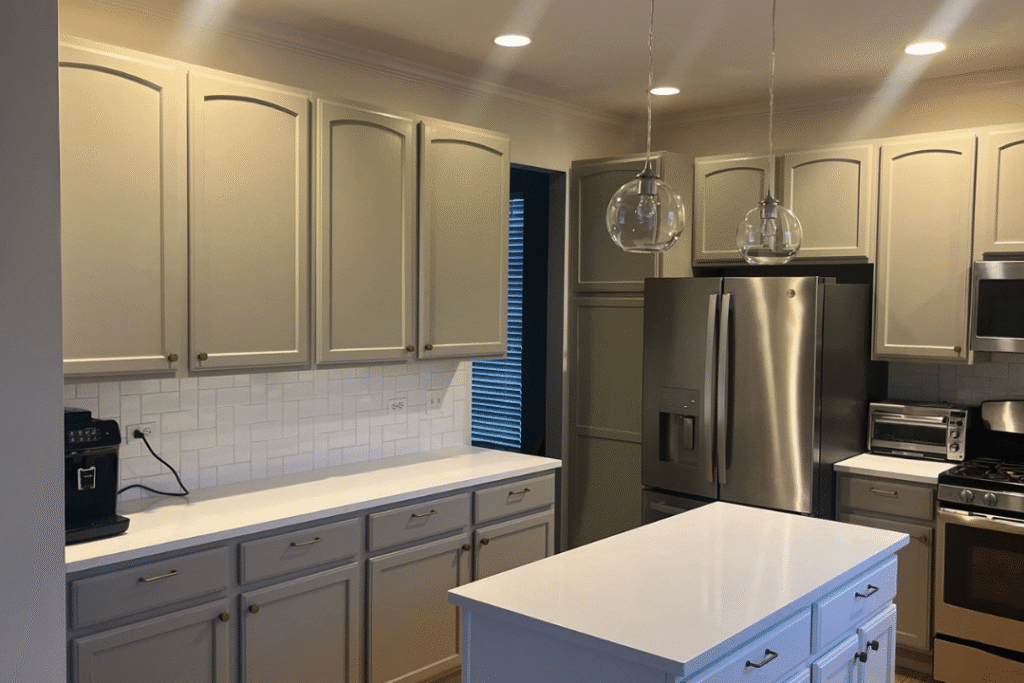Kitchen Cabinet Refinishing Project Cream and gray painted kitchen cabinets with white subway tile backsplash, stainless steel appliances, and blue island