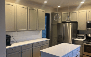 Cream and gray painted kitchen cabinets with white subway tile backsplash, stainless steel appliances, and blue island