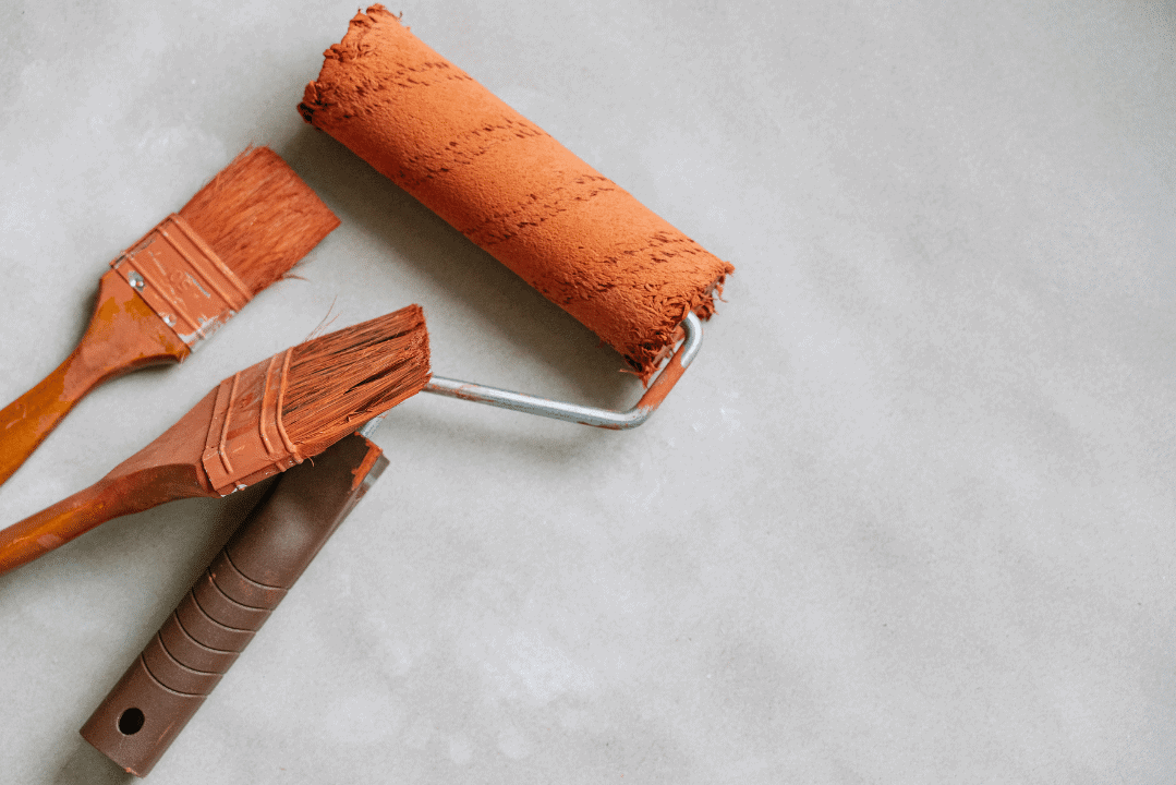 Orange Paint Brushes And Roller Orange paint roller and two orange brushes with wooden handles arranged on white surface.