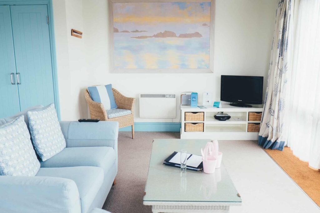 Light Blue Residential Living Room Light blue residential living room with white walls, turquoise accent door, blue upholstered sofa, wicker chair, and coastal