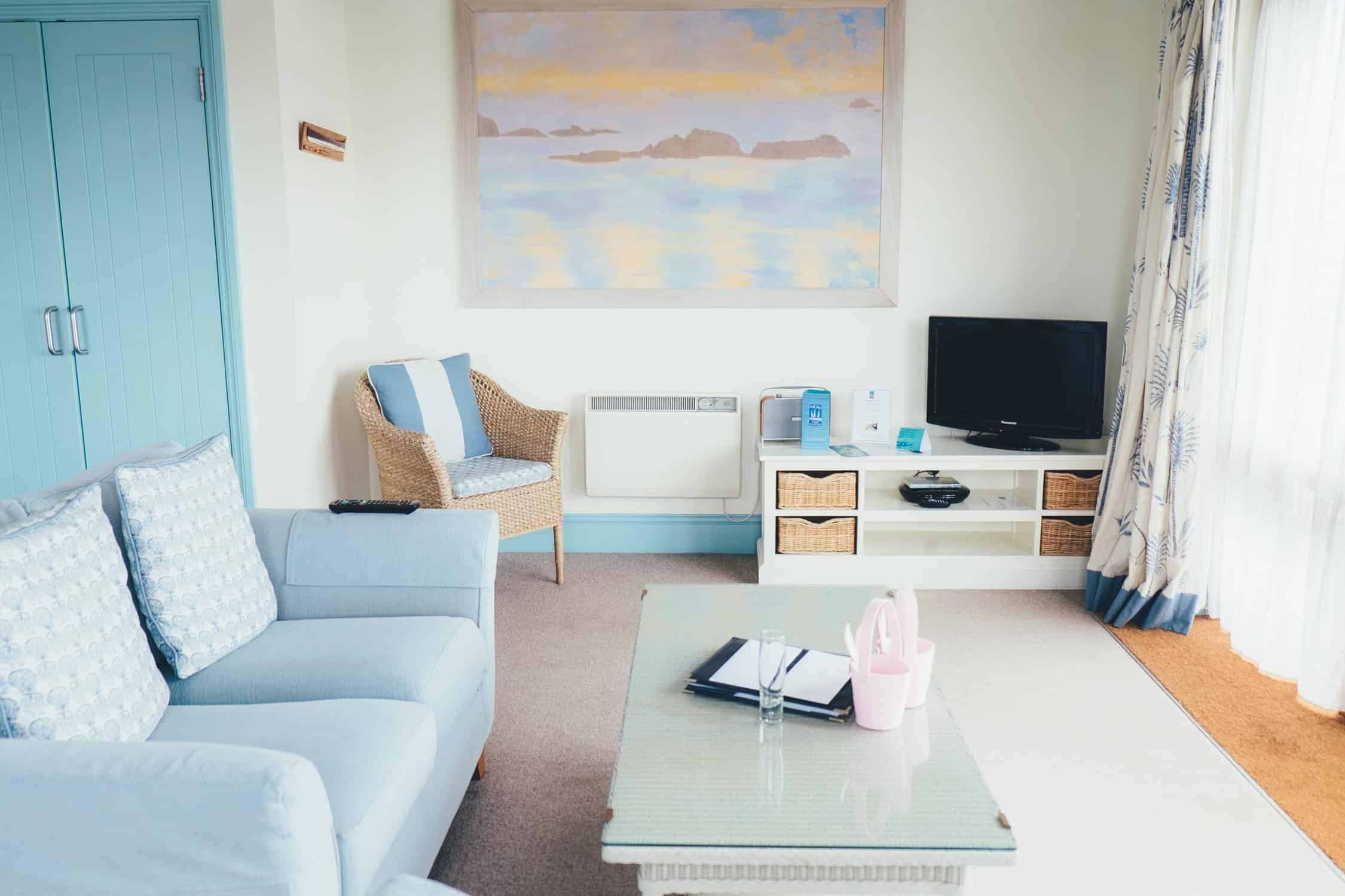 Light Blue Residential Living Room Light blue residential living room with white walls, turquoise accent door, blue upholstered sofa, wicker chair, and coastal