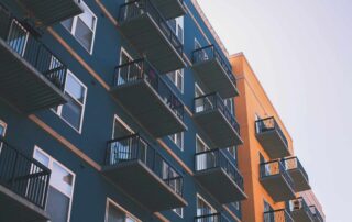 Teal and orange painted multi-story residential building with metal balconies and white-trimmed windows