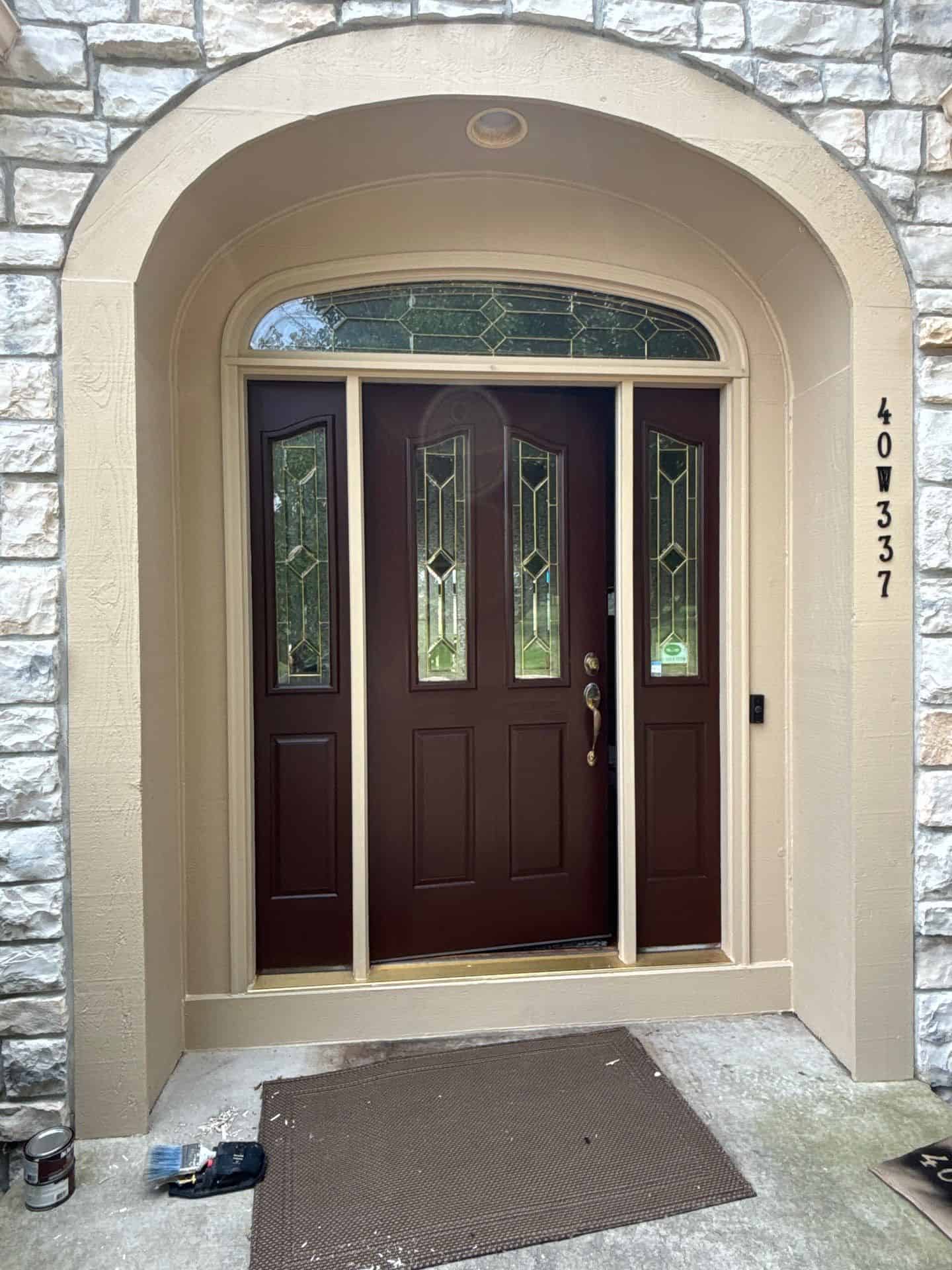 Cream Arched Entryway With Dark Wood Door Cream-painted arched residential entryway with light stone surround, dark wood door with leaded glass panels, and side
