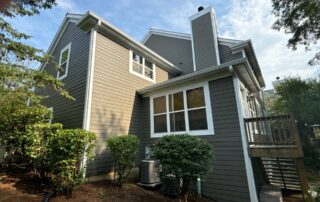 Dark gray and cream two-story residential home with white-trimmed windows, metal railings, and composite deck.