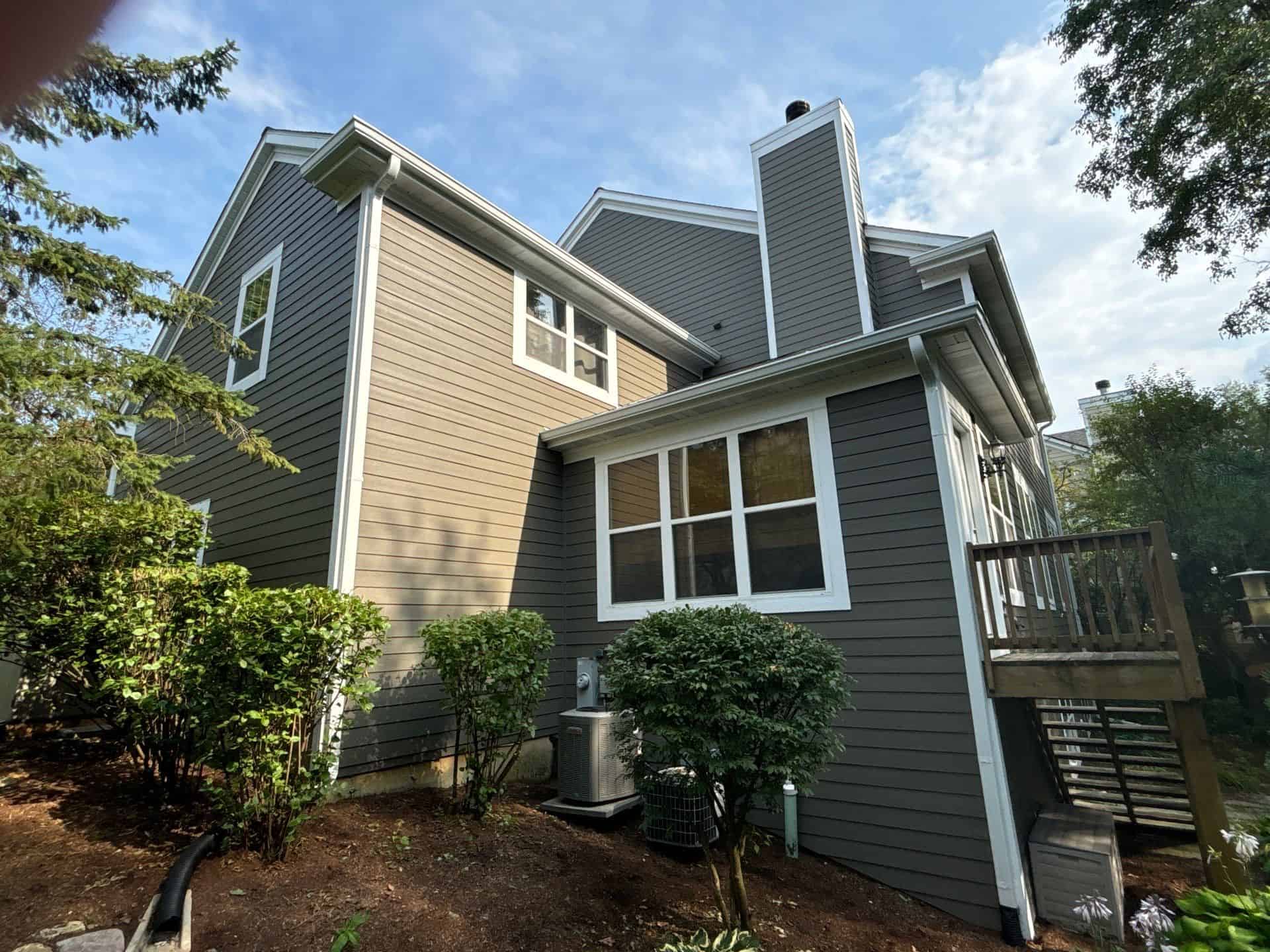 Dark Gray Residential Home Exterior Dark gray and cream two-story residential home with white-trimmed windows, metal railings, and composite deck.