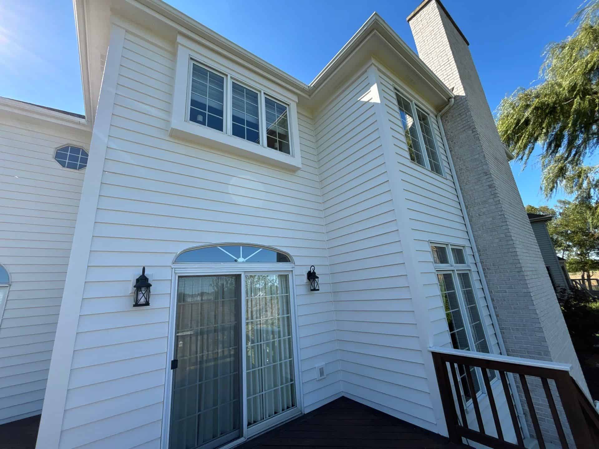 White Residential Home Exterior White-painted two-story residential home exterior with horizontal siding, white-trimmed windows, and dark composite deck