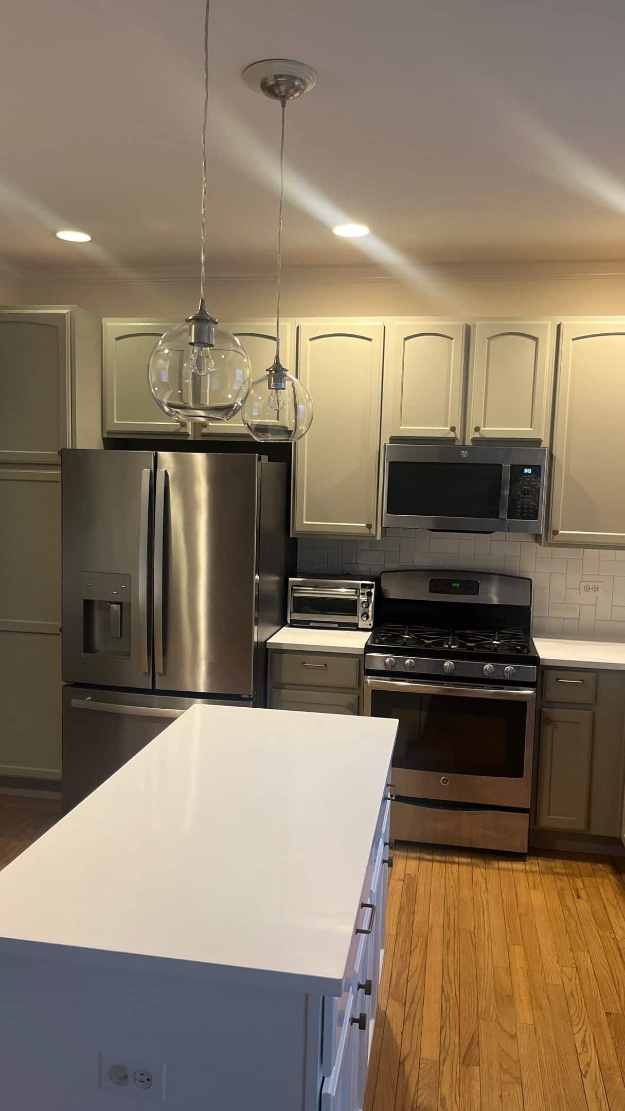 Cream Kitchen Cabinetry Residential Cream-painted residential kitchen with white quartz island, stainless steel appliances, white subway tile backsplash, and