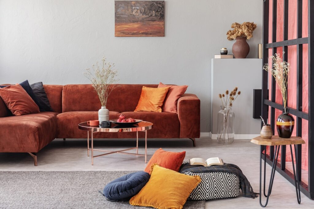 Rust Orange Living Room Interior Rust-orange painted residential living room with white walls, terracotta sectional sofa, copper coffee table, and pink