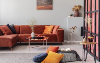Rust-orange painted residential living room with white walls, terracotta sectional sofa, copper coffee table, and pink
