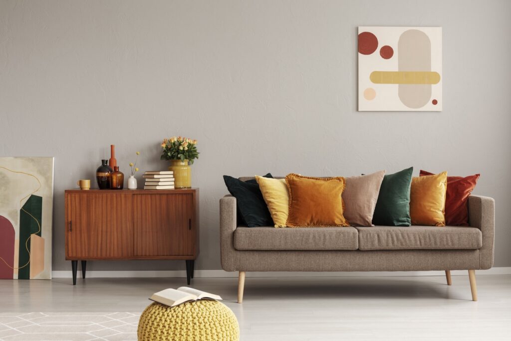 Taupe Living Room Interior Paint Taupe-painted residential living room with cream sofa, warm wood sideboard, and modern abstract wall art.