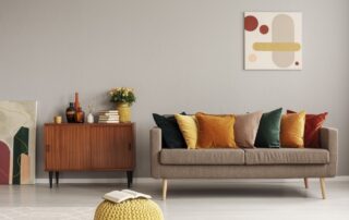 Taupe-painted residential living room with cream sofa, warm wood sideboard, and modern abstract wall art.