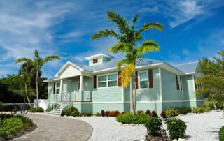 Light blue residential home exterior with white trim, metal roof, covered porch, and brick paver driveway in Saint Charles