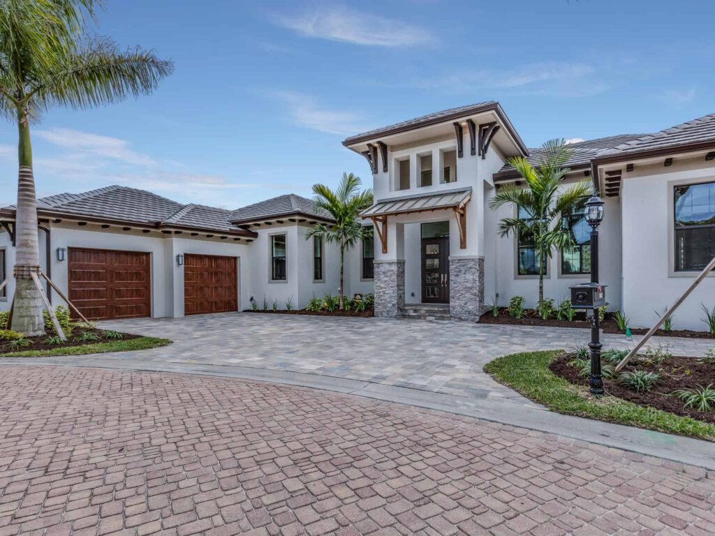 White Exterior Residential Home White-painted residential home exterior with dark wood garage doors, stone accents, and dark-trimmed windows.