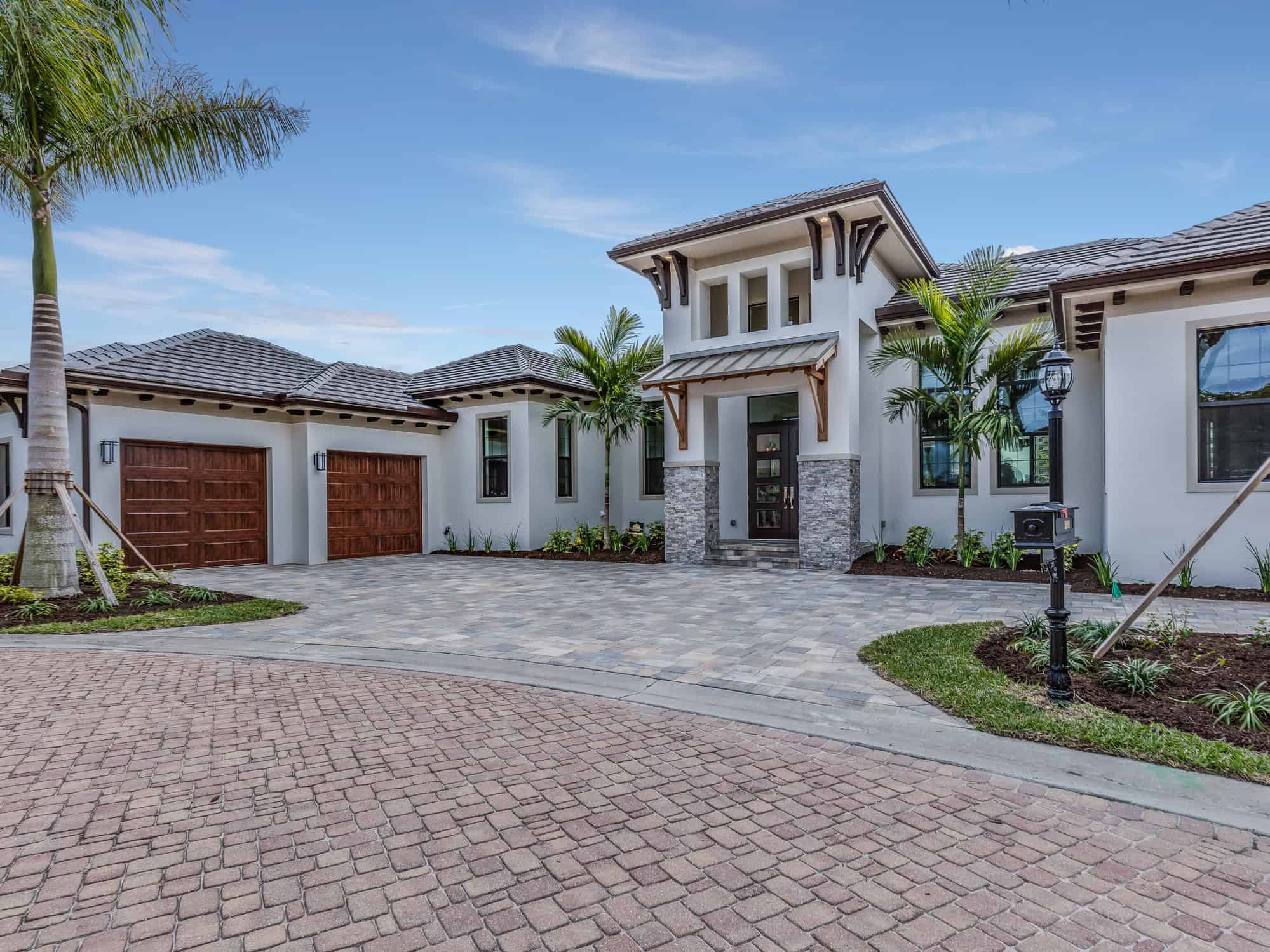 White Exterior Residential Home White-painted residential home exterior with dark wood garage doors, stone accents, and dark-trimmed windows.