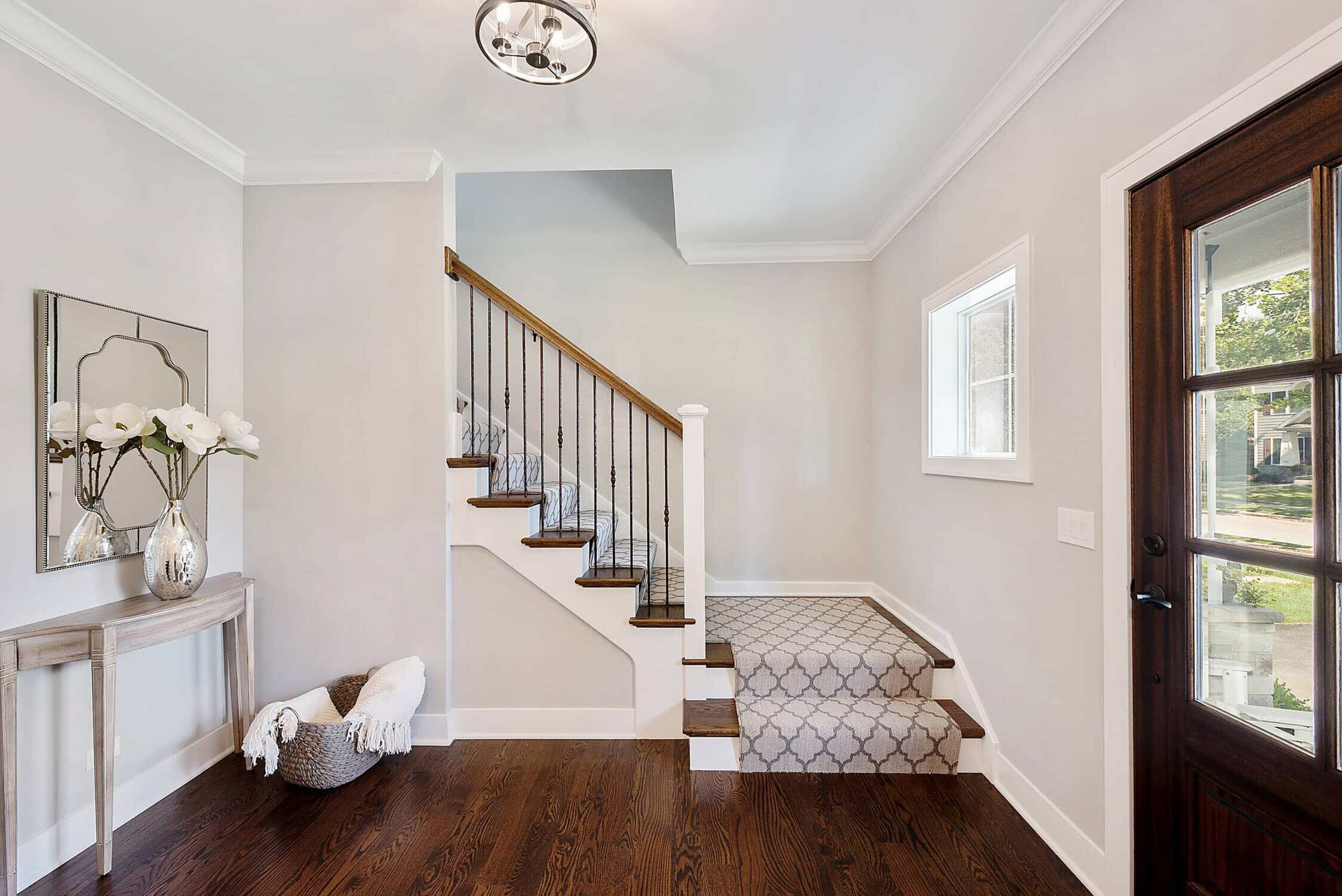 Cream Interior Entryway Painting Cream-painted interior entryway with white ceiling, dark wood staircase, and hardwood floors in residential home.