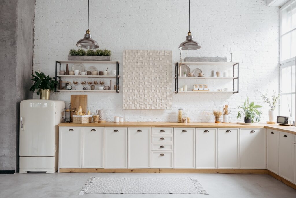 White Kitchen Cabinetry Interior White-painted kitchen cabinetry with wood countertops, open shelving, cream subway tile backsplash, and industrial pendant