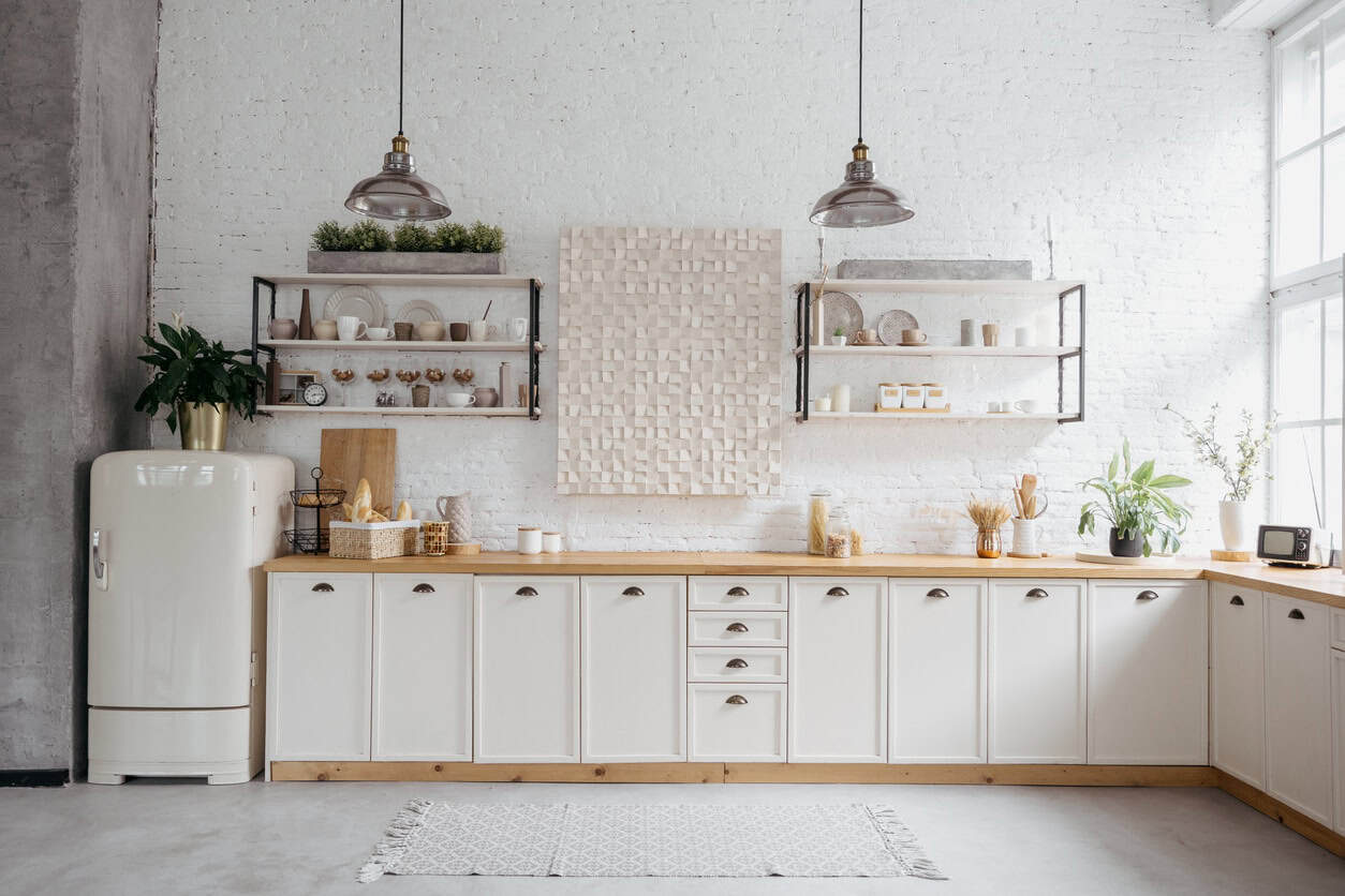 White Kitchen Cabinetry Interior White-painted kitchen cabinetry with wood countertops, open shelving, cream subway tile backsplash, and industrial pendant
