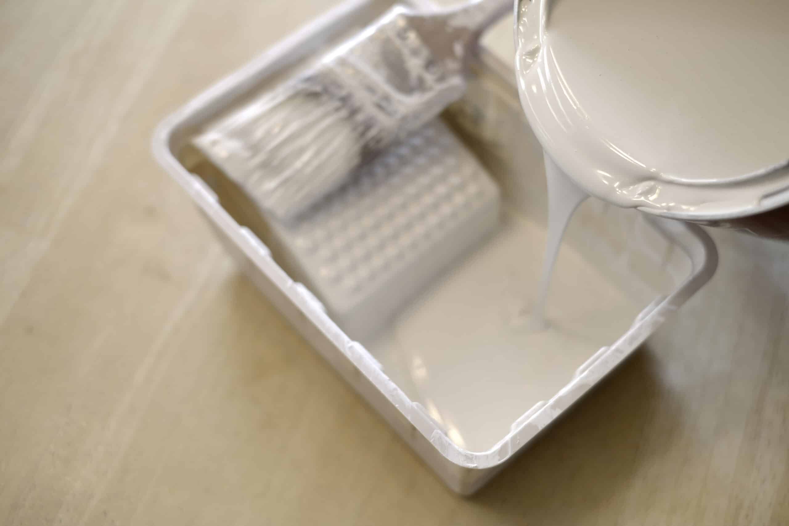 Paint Brush and Roller Tray White paint tray with foam brushes and paint can positioned on neutral surface.