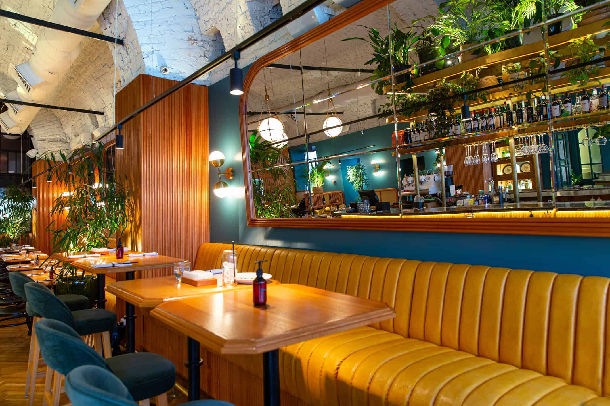 Commercial Interior Cafe Painting Modern commercial cafe interior with deep teal-painted accent wall, mustard-yellow booth seating, warm wood tables, and