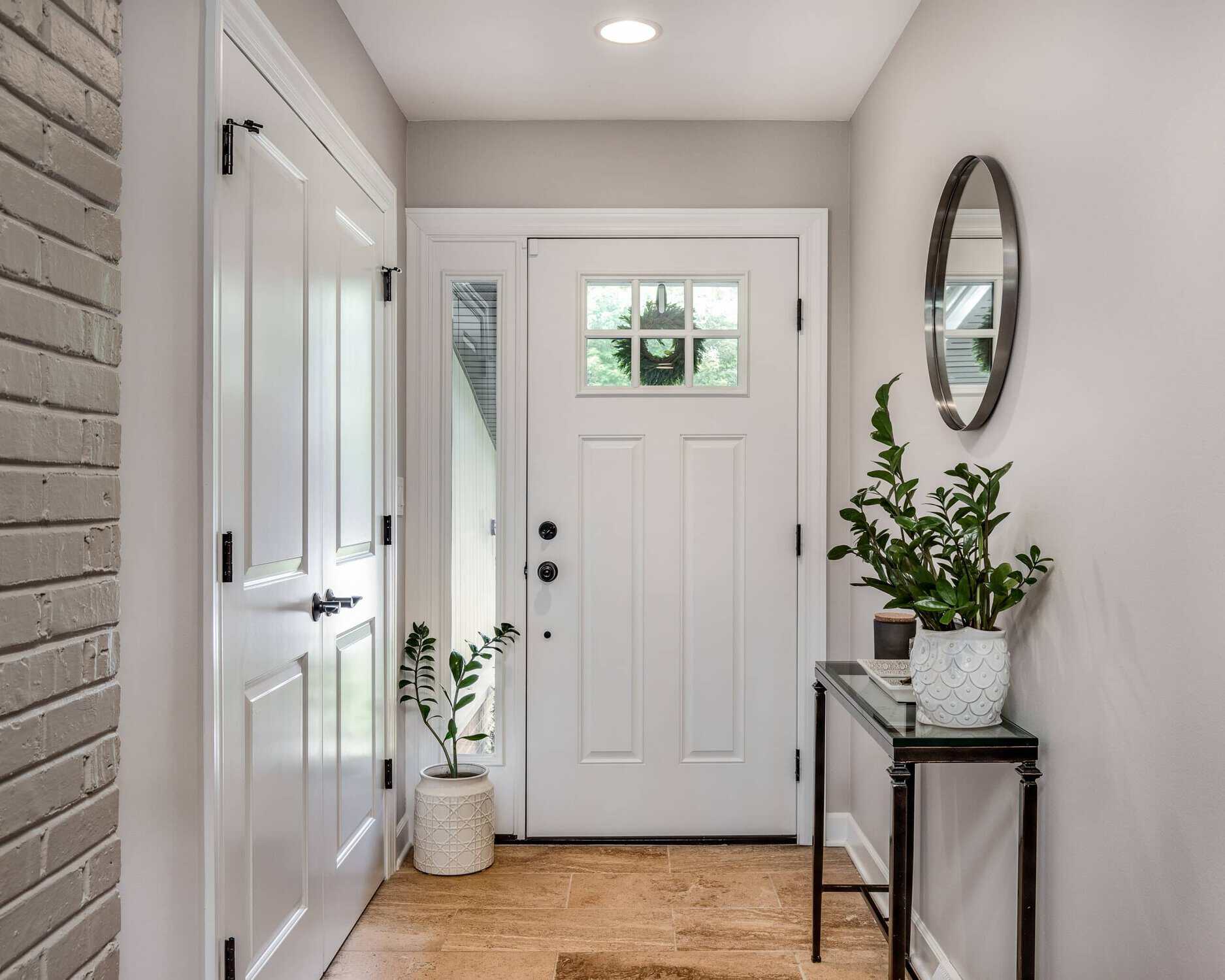 White Interior Entryway Painting White-painted residential entryway with soft gray walls, white six-panel door, and hardwood flooring.