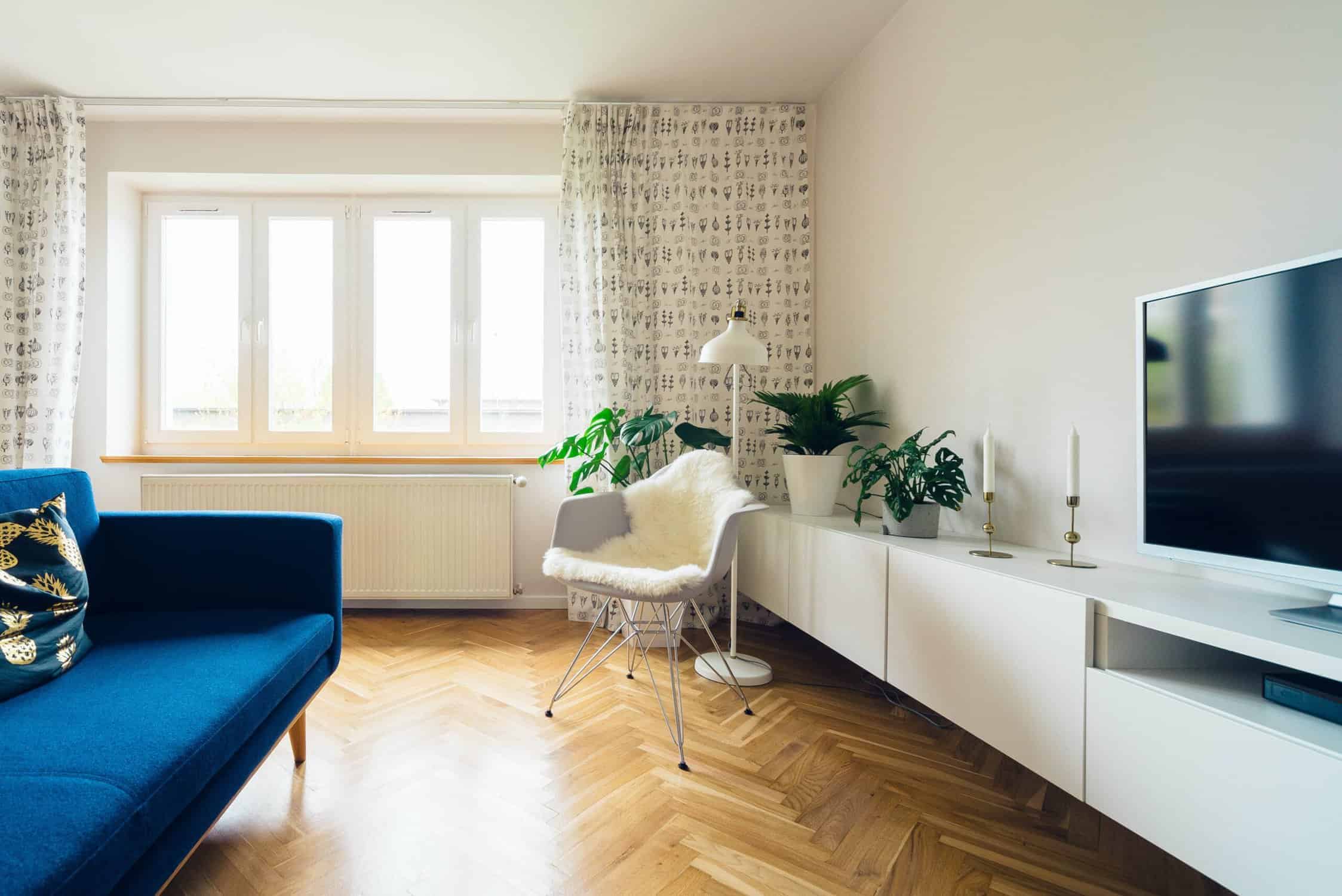 Cream Interior Living Room Walls Cream-painted residential living room with white trim, herringbone wood flooring, blue sofa, and large windows with sheer