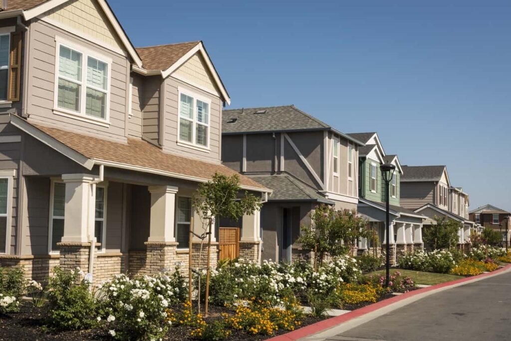 Cream and Charcoal Residential Exterior Row of cream and charcoal-painted residential homes with white-trimmed windows, covered porches, and brick accents in Saint