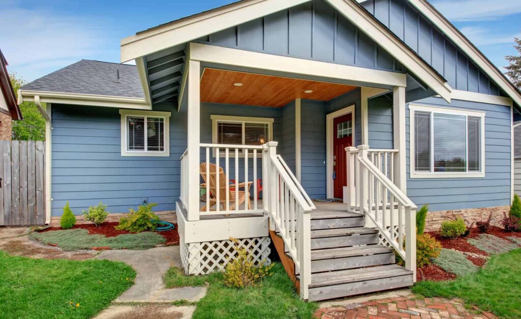 Light Blue Residential Exterior Painting Light blue residential home exterior with cream trim, white railings, red entry door, and covered front porch.