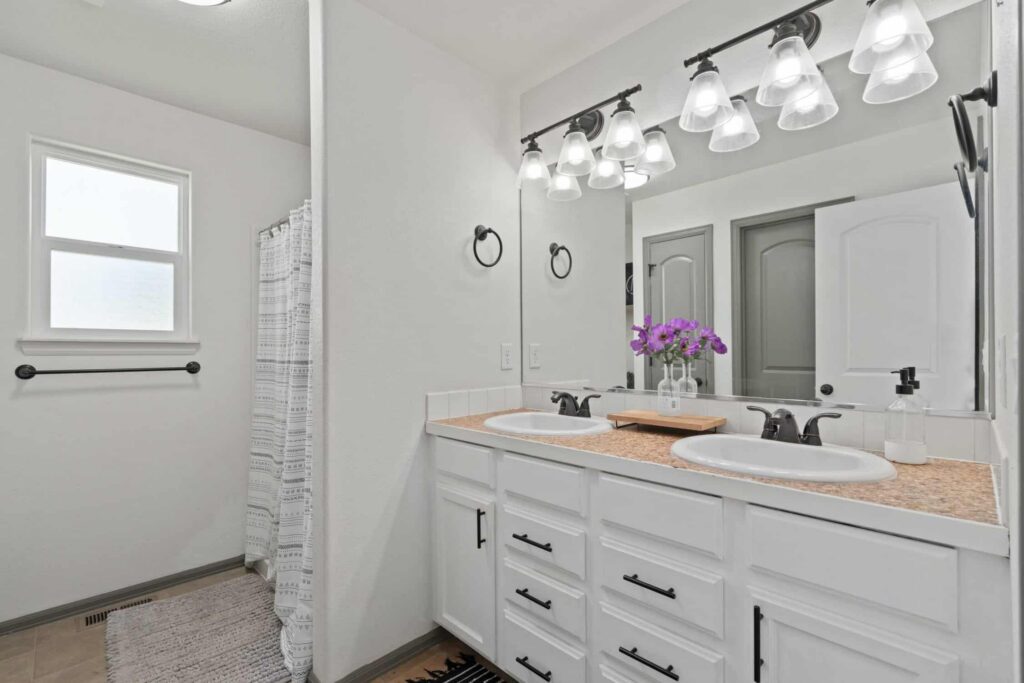 White Painted Bathroom Vanity Bright white-painted residential bathroom with dual vanity, cork countertops, black hardware, and track lighting.