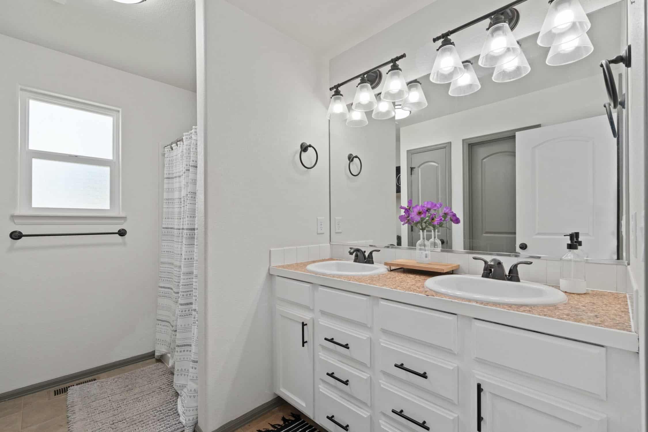 White Painted Bathroom Vanity Bright white-painted residential bathroom with dual vanity, cork countertops, black hardware, and track lighting.