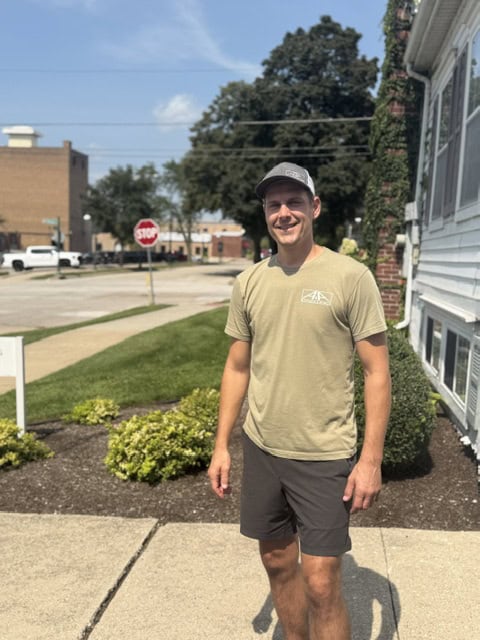 Man in tan t-shirt and sunglasses standing on residential driveway in Saint Charles, IL.